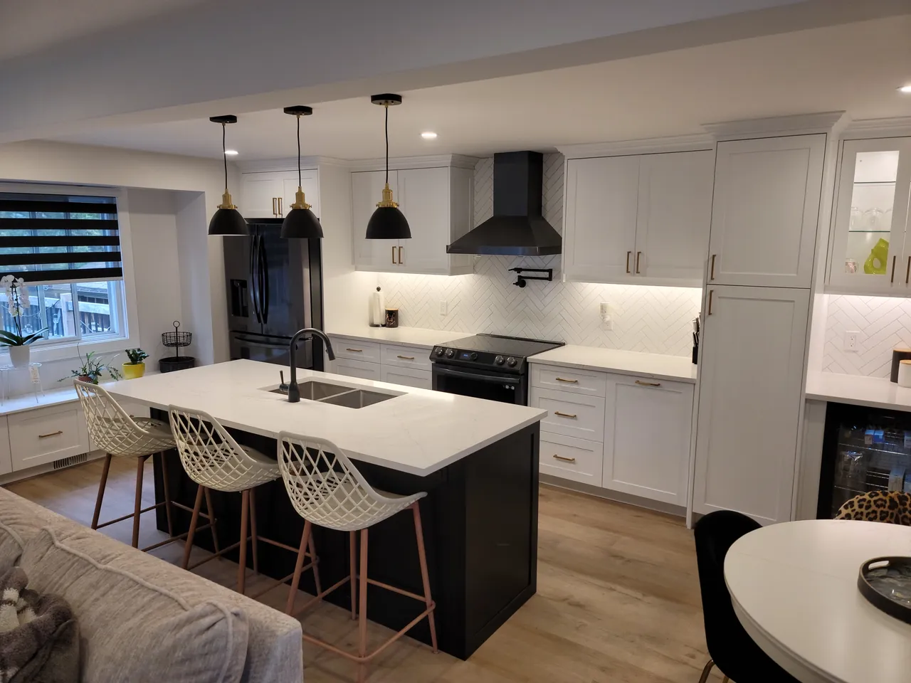 White kitchen with a dark island, black pendant lights and a black range hood