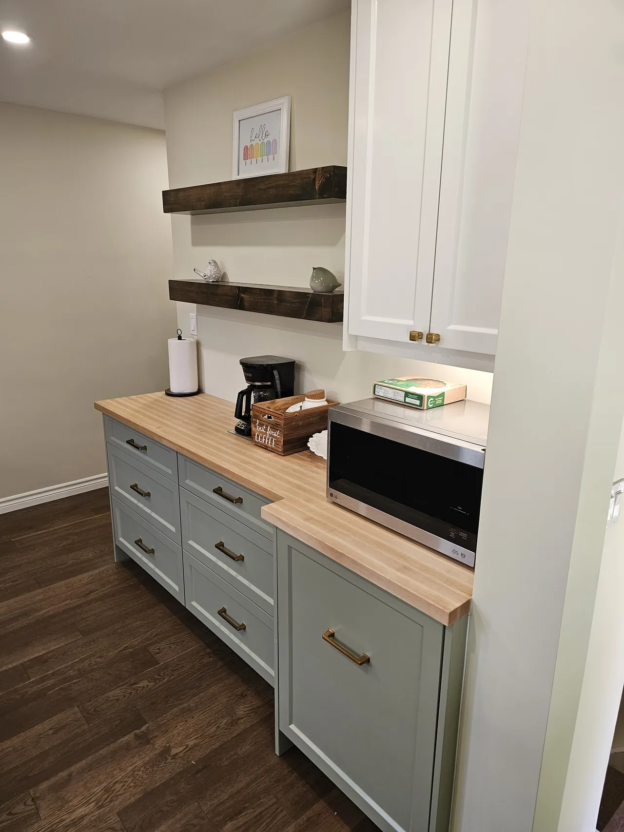 Sage green cabinets with brass pulls and a butcher block top