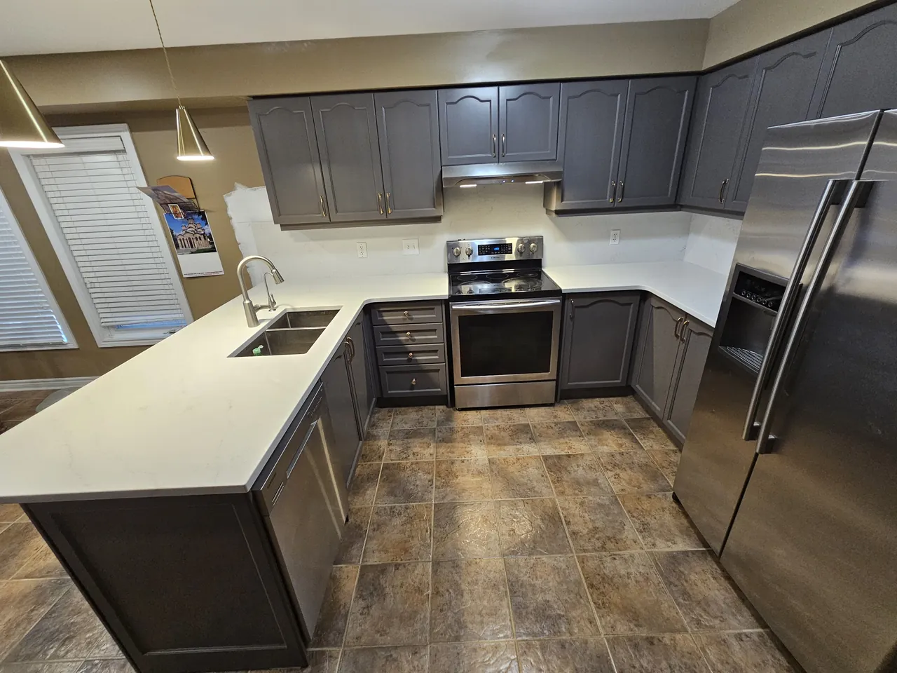 L shaped kitchen with resprayed charcoal cabinets and stainless appliances