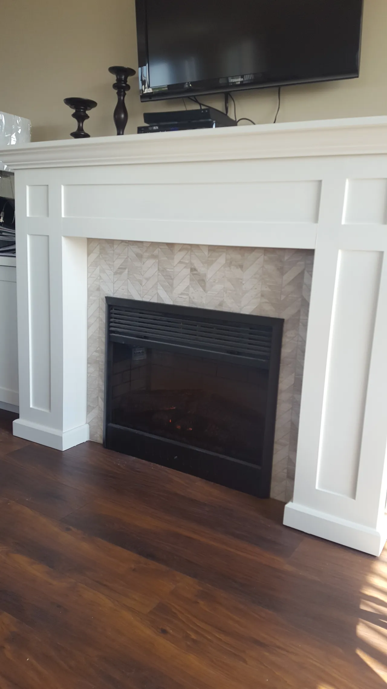 White fireplace mantel surround with a herringbone tile insert
