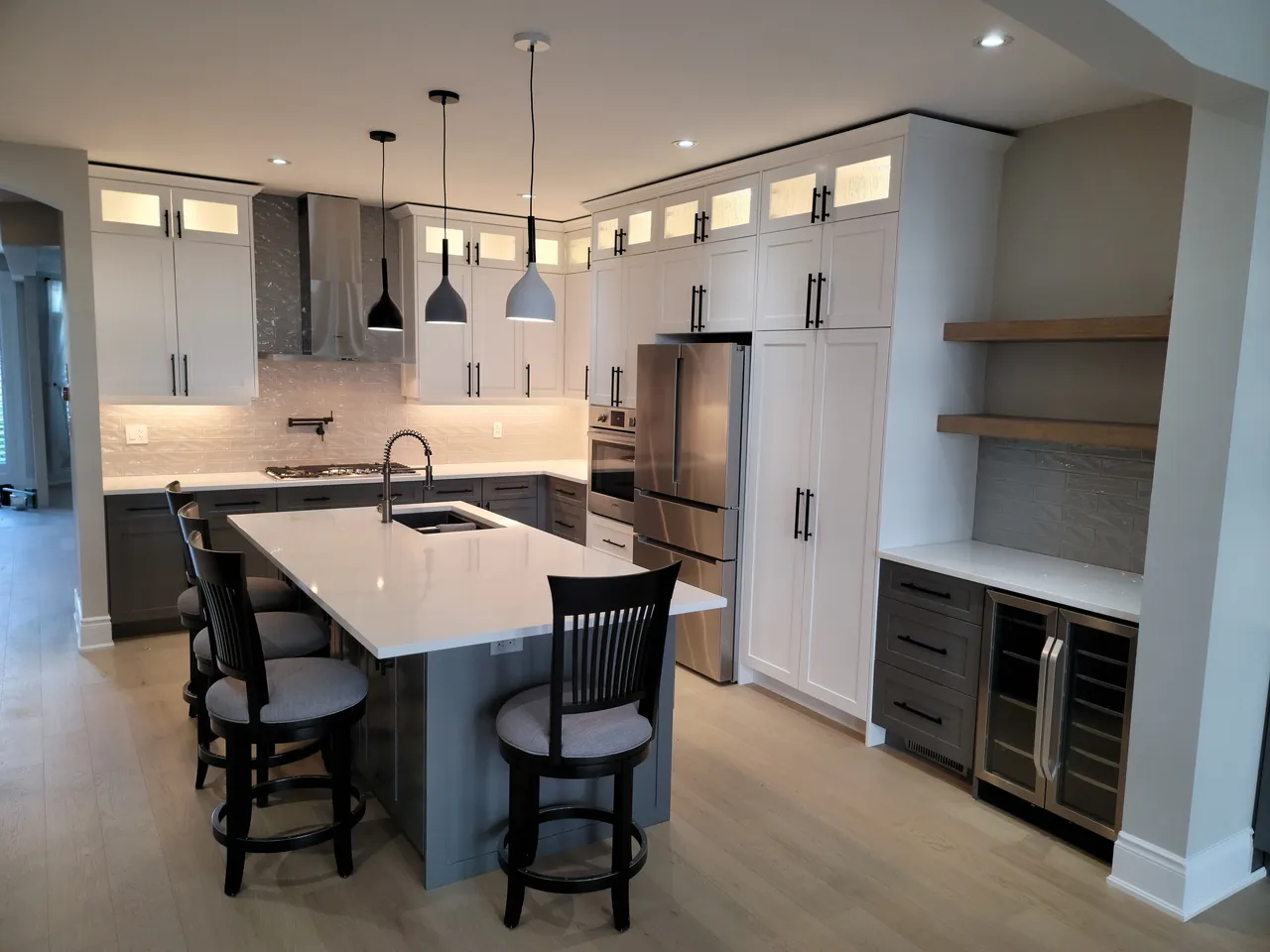 White shaker kitchen with a grey island, pendant lights and glass uppers